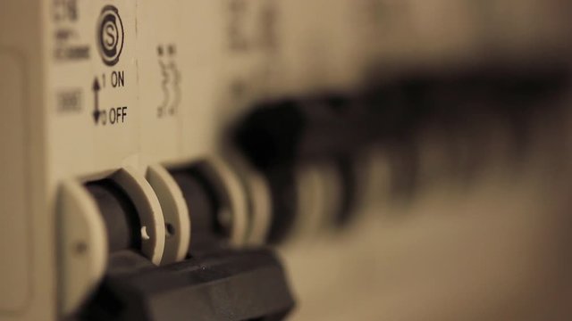 Hand Turning Off Electrical Switch on Circuit Breaker Panel - Close Up  