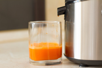 detox. smoothies. the process of making juice in the kitchen. A glass of fresh carrot juice. carrot...