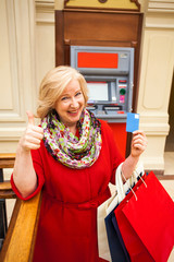 Happy pensioner withdraws cash from an ATM