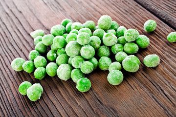 Heap of frozen pea on a old wooden table.