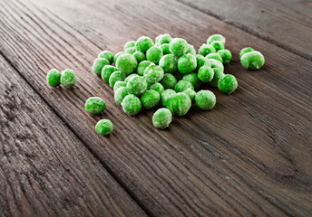 Heap of frozen pea on a old wooden table.