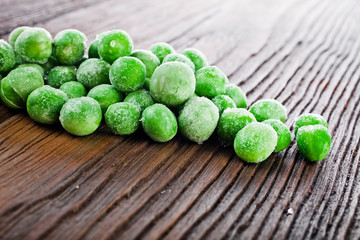 Heap of frozen pea on a old wooden table.