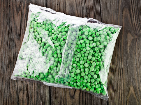 Packet of frozen pea on a old wooden table.