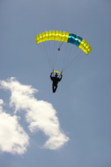 Skydiver under a canopy of a parachute against a blue sky and clouds in backlighting, close-up.