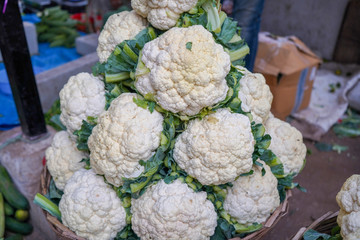 Fresh cauliflower for sale in the market, Group of cauliflowers with green leaves,Pile of organic cauliflower for sale at local farmers market.