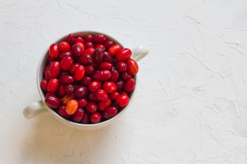 Dogwood is a sweet and sour red fruit. medicinal plant. ripe vitamin berries. Dogwood on a wooden white background in a white plate with space for text. The concept of a healthy lifestyle. gardening