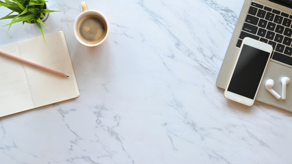 Marble office desk with Laptop, black blank screen smartphone, wireless earphone, pencil, notes and potted plant putting. Flat lay working equipment concept.