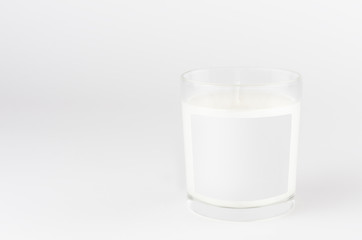 Candle in transparent glass with white blank label on white background, mock up for branding identity product, advertising, presentation, design packing.