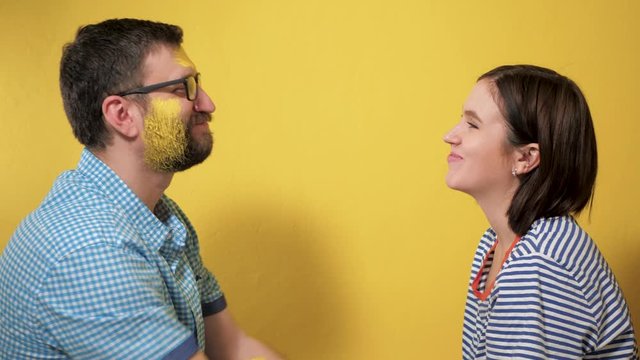 Man and woman kiss rejoicing at end of painting walls. They are both stained with yellow paint. Painting repair work over concept. Slow motion and close up