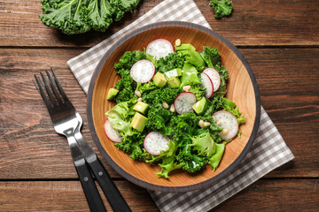 Delicious kale salad on wooden table, flat lay