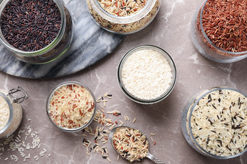 Flat lay composition with brown and polished rice on grey marble table