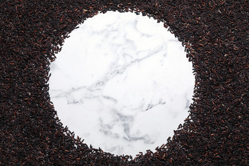 Frame made of brown rice on white marble table, top view. Space for text