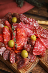 Tasty salami with other delicacies served on wooden table