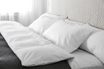 Bed with soft fluffy pillows at home