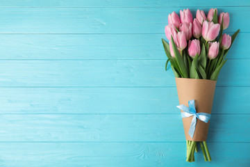 Beautiful pink spring tulips on light blue wooden background, top view. Space for text