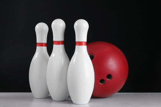 Red bowling ball and pins on grey table