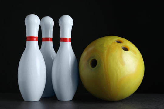 Yellow bowling ball and pins on black stone table