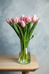 Beautiful pink spring tulips in vase on wooden table