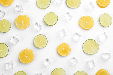 Lemonade layout with ice cubes, lime and orange slices on white background, top view