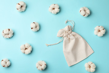Cotton eco bag and flowers on light blue background, flat lay