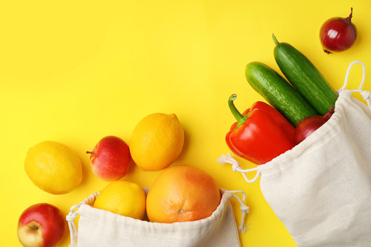 Cotton Eco Bags With Fruits And Vegetables On Yellow Background, Flat Lay. Space For Text