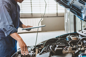 Asian Man mechanic inspection writing note on clipboard.Blue car for service maintenance insurance...