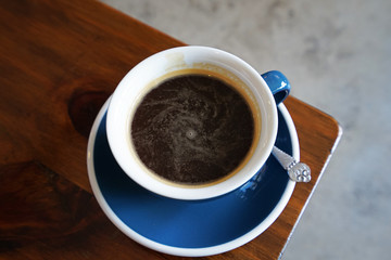 Close up ceramic porcelain cup of Hot black coffee on wooden table
