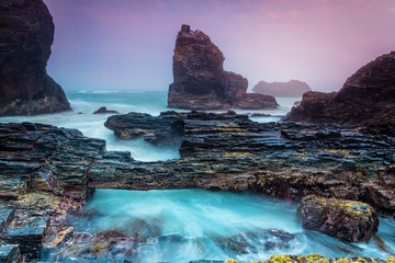Natural bridge over tidal waters along craggy coastline © Leah-Anne Thompson