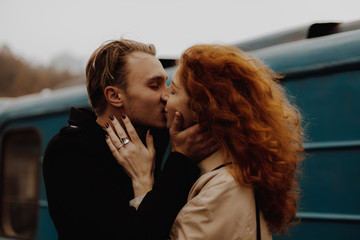 Young couple in love kissing against train in train station.