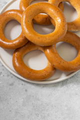 Bagels with poppy seeds on a white ceramic plate on a gray kitchen table. Homemade cake