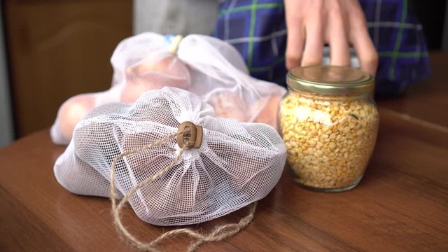 Zero waste, plastic free concept. Young man returned home after shopping grocery at farmers market. Reusable eco bags and glass jars for shopping, packing and storage