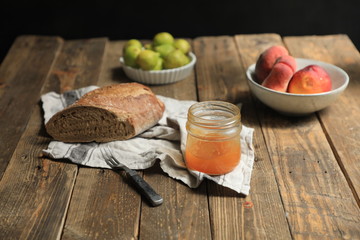 food still life on a rustic wooden table with figs bread and orange marmalade on a dark background