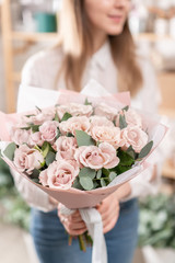 Beautiful bouquet of pastel roses in womans hands. the work of the florist at a flower shop. Delivery fresh cut flower. European floral shop.