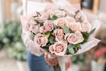 Beautiful bouquet of pastel roses in womans hands. the work of the florist at a flower shop....
