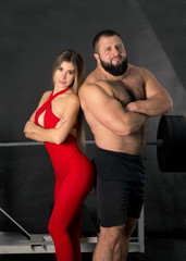 Fototapeta na wymiar A couple of sporty people, a strong man and a fragile girl in getting ready for training in the gym. Beautiful, sporty, trained body, powerlifter and fitness girl. Beautiful couple man and woman