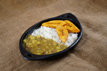 artisanal mud dish containing meat hash with rice and slices of fried plantains on a jute mat © Carlos Mina Yáñez
