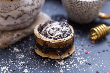 Raw vegan poppy rolls on a black table with raw ingredients. Vegetarian sweets.