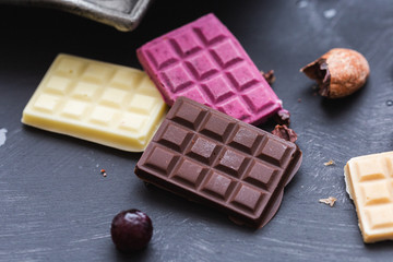 Colorful raw vegan and frozen chocolate bars on a black table top.