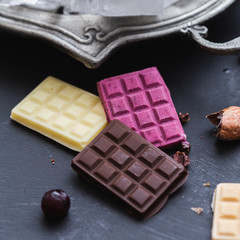 Colorful raw vegan and frozen chocolate bars on a black table top.