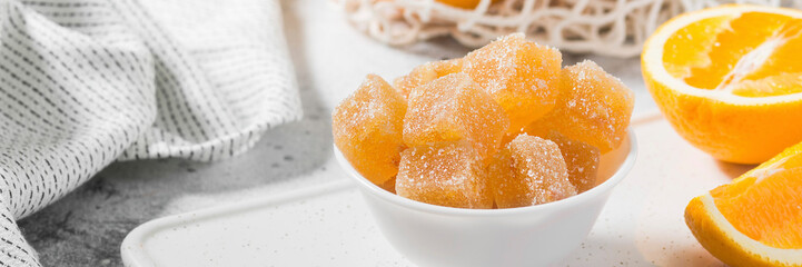 Sprinkle the orange marmalade with sugar in a white ceramic bowl on a light gray table. Banner