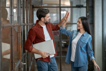 Young girl in jeans jacket doing high five her colleague