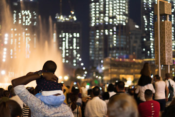 Obraz premium Crowd of visitors contemplating the show around the dancing fountains at night outside the Dubai Mall in the United Arab Emirates.