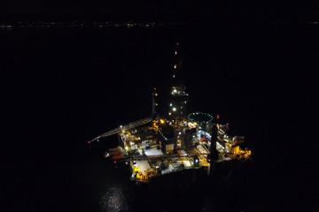 Towing of the oil platform. Oil platform at night in the light of its own lighting. Drilling...