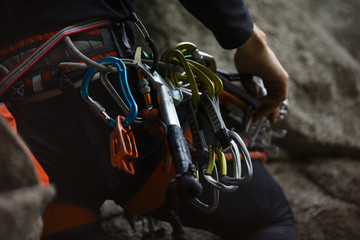 Numerous climbing equipment fixed on the harness of the climber, close-up.