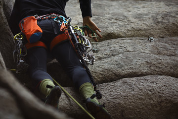 Climbing equipment on the harness of the climber on the background of a technical terrain, close-up.