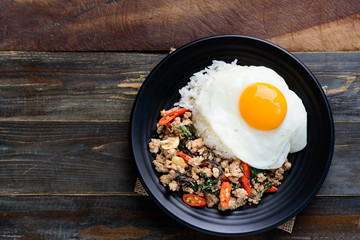 Thai food (Pad Kaprao Moo Kai Dao), stir-fried holy basil with minced pork and fried egg on wooden background