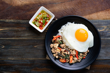 Thai food (Pad Kaprao Moo Kai Dao), stir-fried holy basil with minced pork and fried egg on wooden background