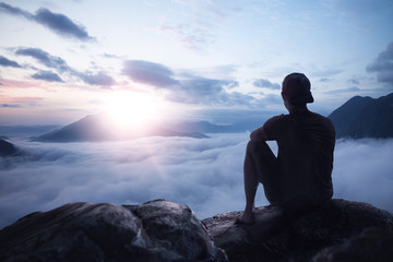Young man enjoying the sunrise on a mountain peak