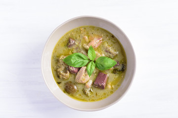 Thai green curry chicken in a bowl on white background, top view