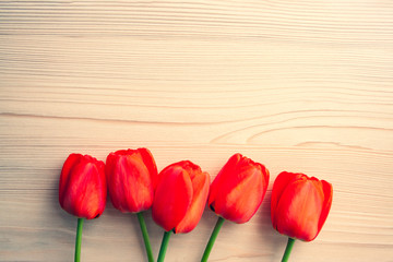 Beautiful red tulips top view on wooden bright background with copyspace. Celebration, postcard template for mother day, women day, valentine, toned